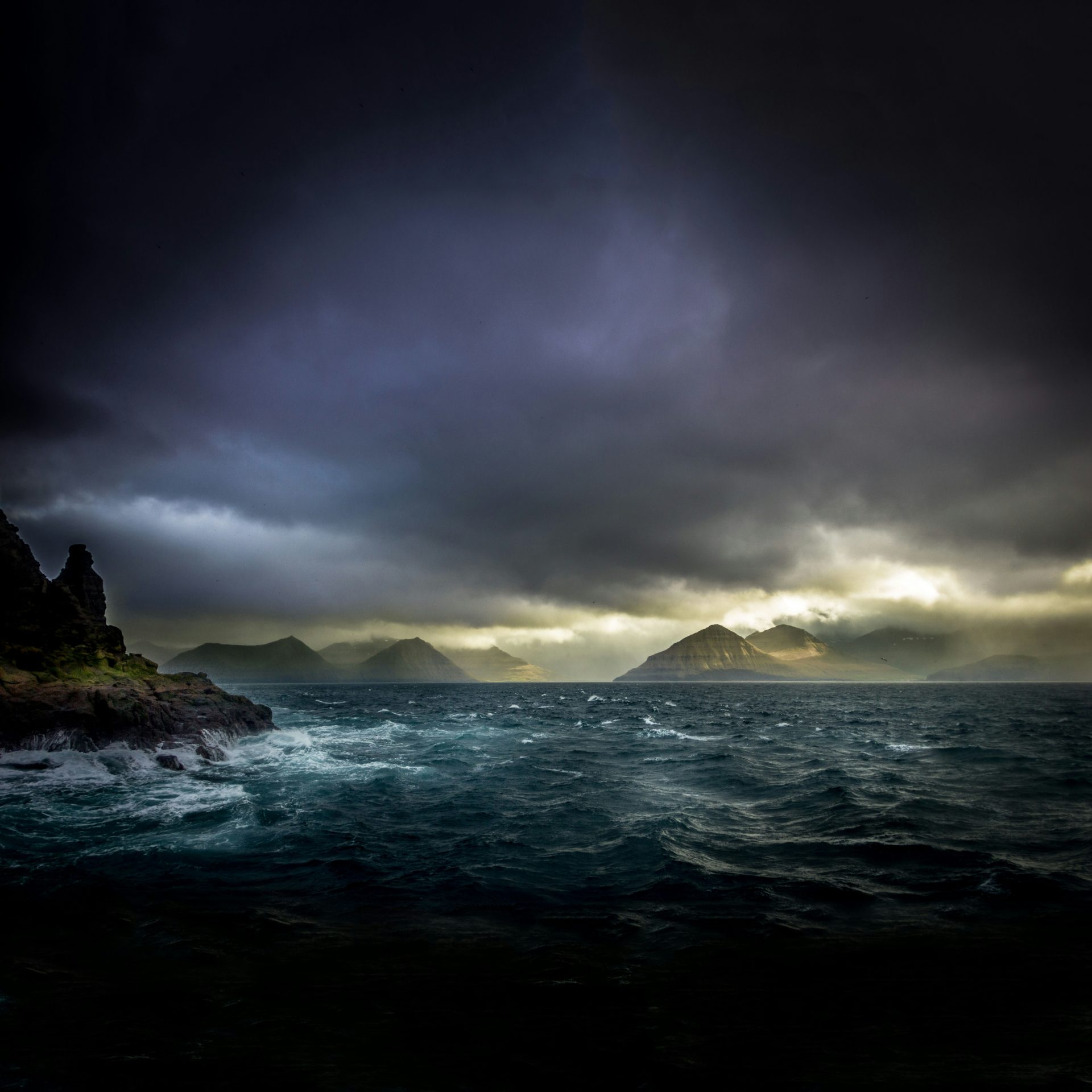 landscape photo of waters, mountains, and black clouds